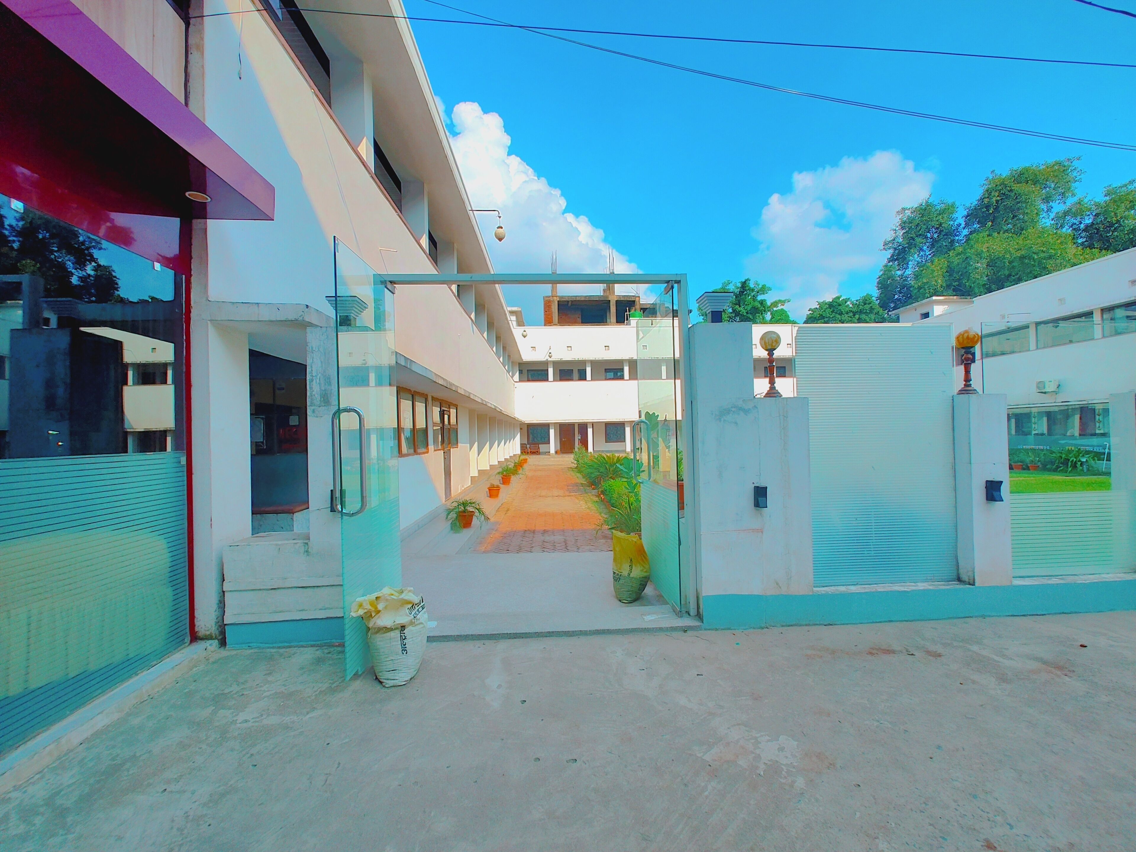 A building with a covered walkway, potted plants, and a clear sky.