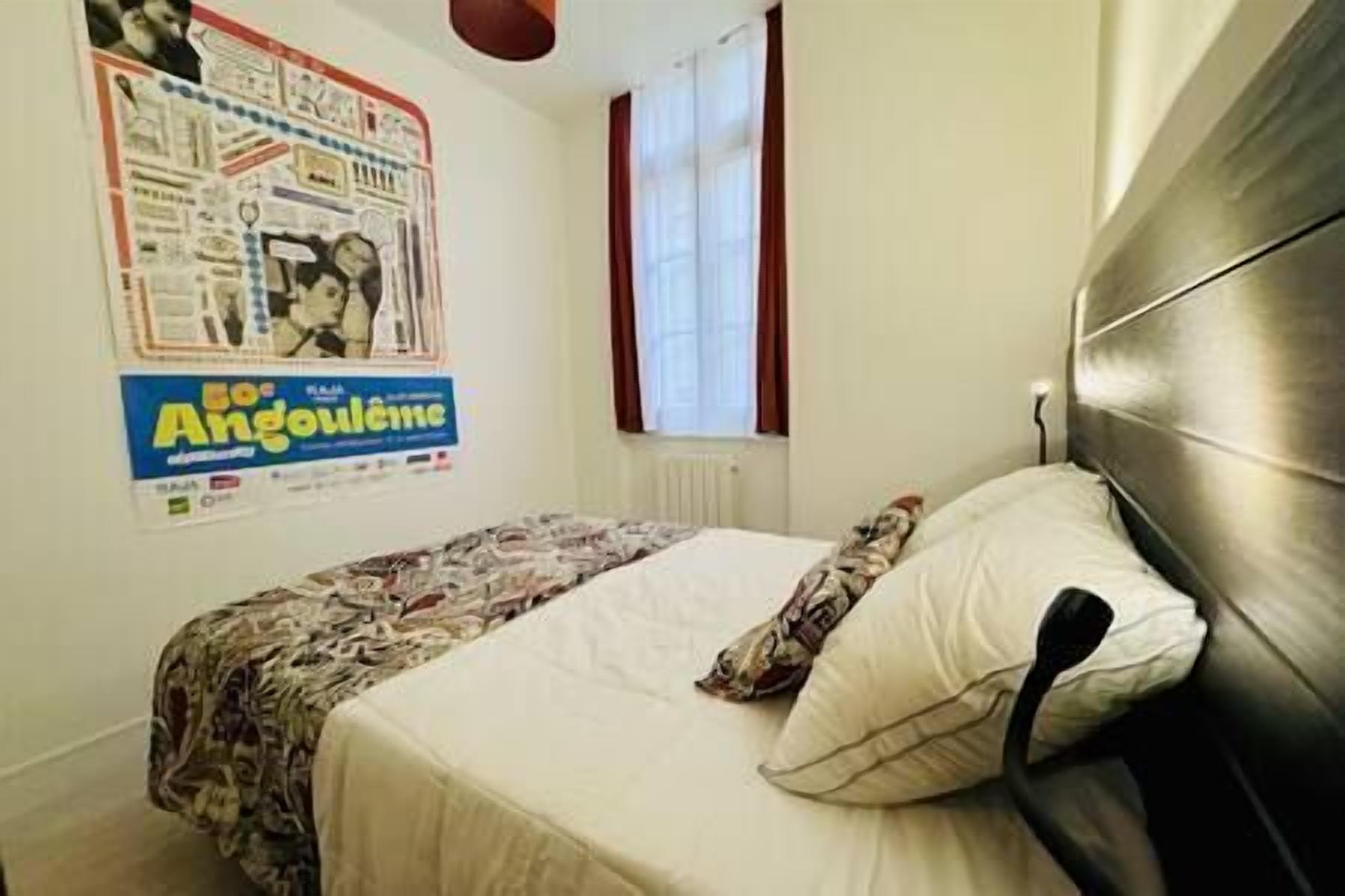 A bedroom with a bed, a poster on the wall, and a window with curtains.