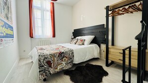 Ein Schlafzimmer mit einem Bett, einer Hängelampe, einer Holzbank und einem Fellteppich.