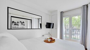 Een hotelkamer met een groot bed, een flatscreen televisie, een raam met gordijnen en een dienblad met ontbijtartikelen.
