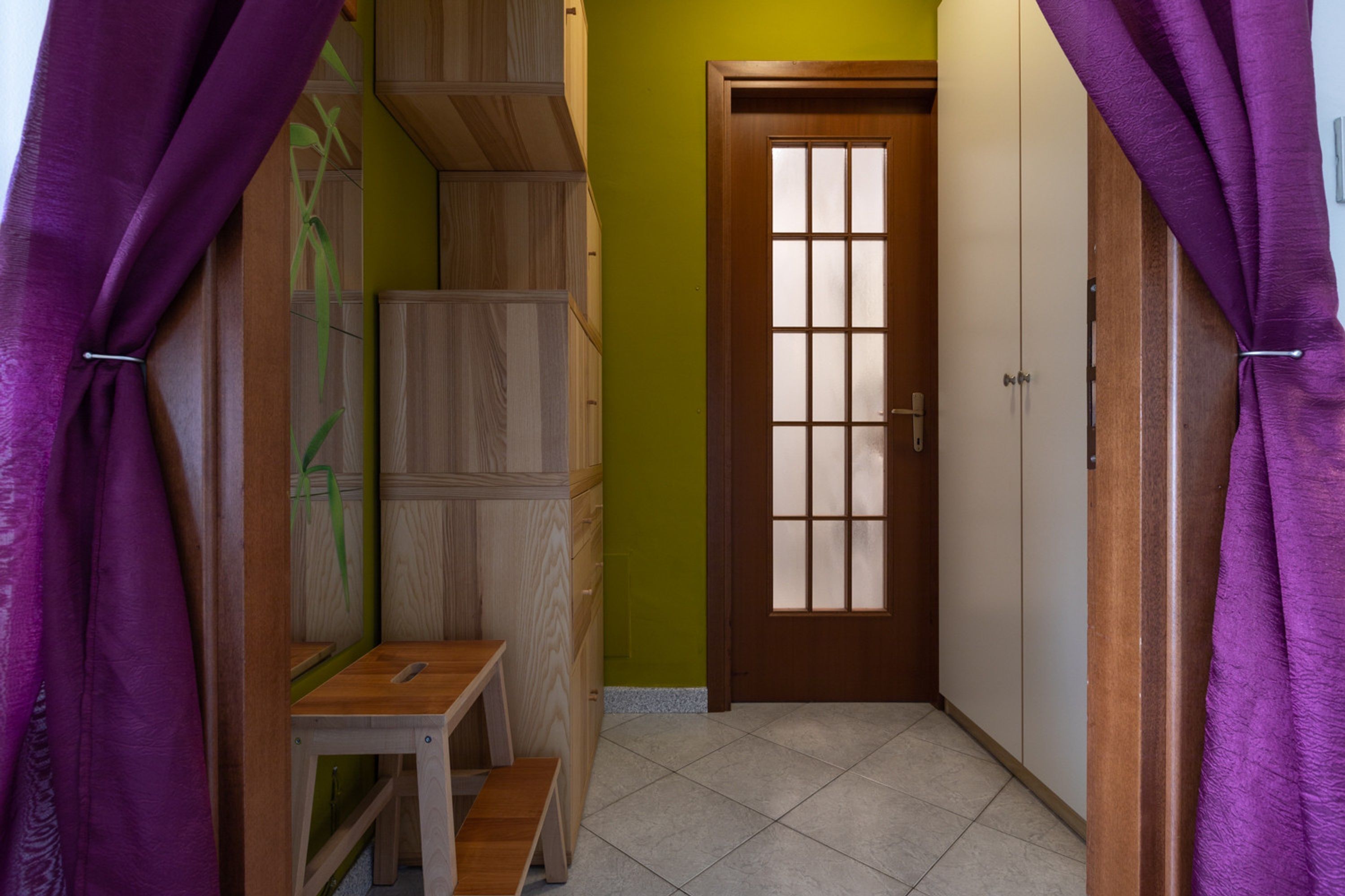 Un pasillo con una puerta de madera, una mesita y un banco.