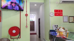 A hotel reception area with a television, a red fire hose, a clock, and a decorative cat statue. - Hotel O Signature Inn Miri (Miri)