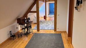 Un loft espacioso con techos altos, vigas de madera a la vista, una zona de estar acogedora con un piano y vistas al exterior.