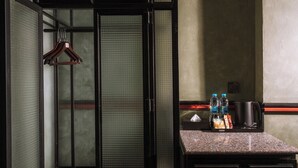 Een hotelkamer met een schuifdeur, een kleine kitchenette met een koffiezetapparaat en een waterfles op het aanrecht.