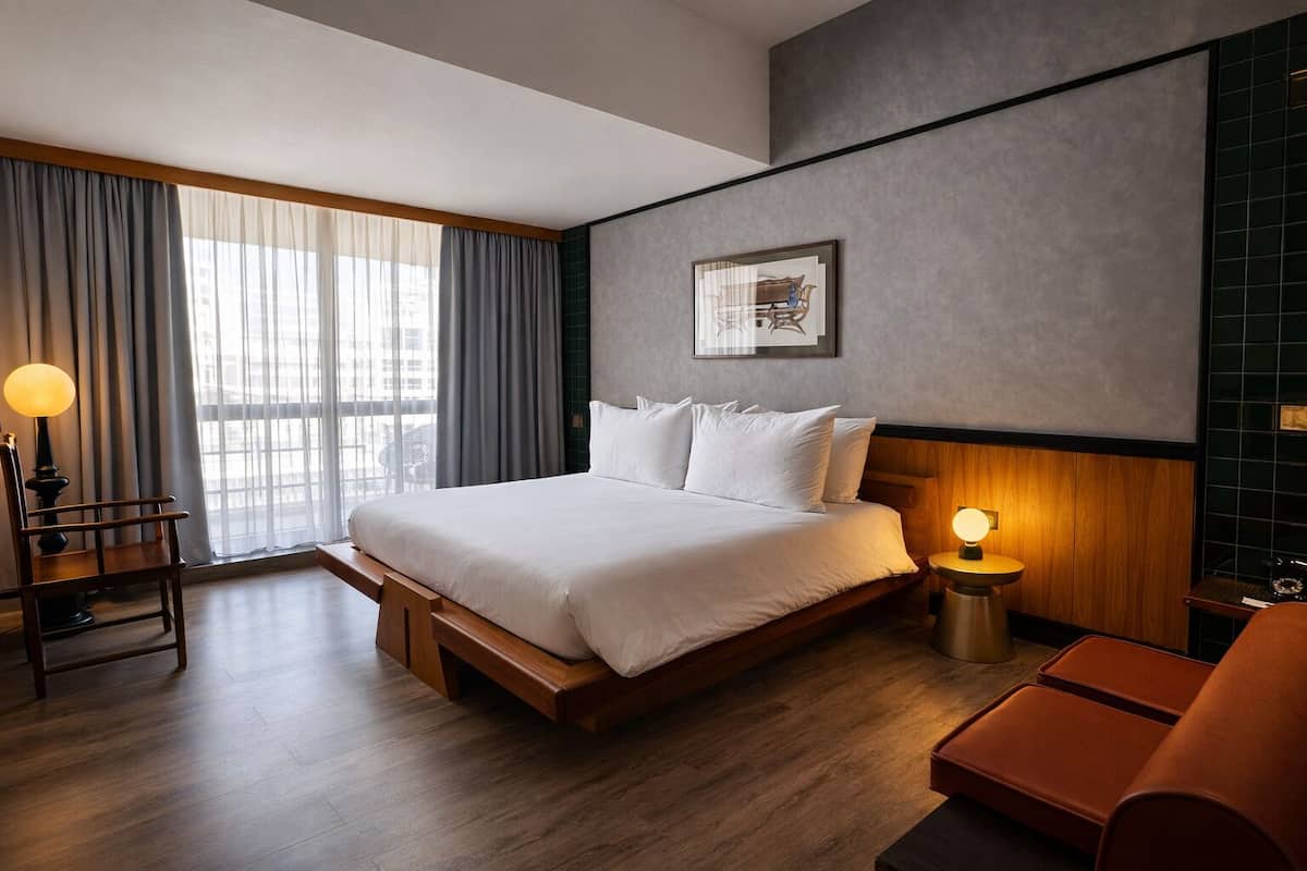 Une chambre d’hôtel moderne, dotée d’un grand lit, d’un bureau et d’une chaise.