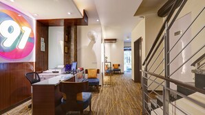 A hotel reception area with a desk, chairs, a large illuminated number '91', and a staircase marked 'STAFF ONLY'. - Hotel 91 Golf Course Road (Gurugram)