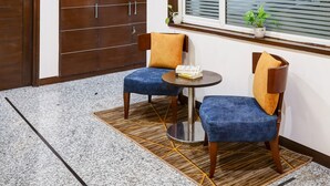A hotel room with a large wooden wardrobe, a round table with two chairs, a chandelier, and a window with blinds. - Hotel 91 Golf Course Road (Gurugram)