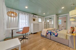 A bedroom with a bed, a desk, a chair, and a dresser. - Pink Bungalow! (Austin)