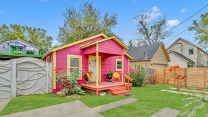A pink house with a porch, a wooden fence, and a green lawn. - Pink Bungalow! (Austin)