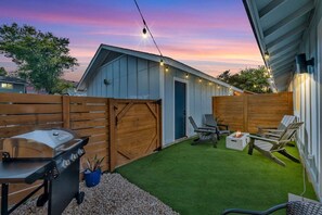 A backyard with a barbecue grill, outdoor seating, and a shed.