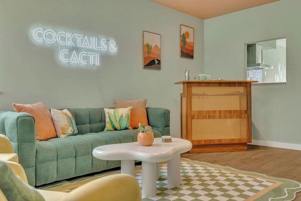 A living room with a green sofa, a white coffee table, and a checkered rug.