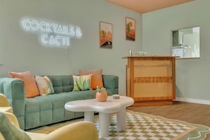 A living room with a green sofa, a white coffee table, and a checkered rug.