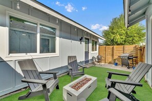 Un patio con sillas Adirondack, una fogata y una cerca de madera.