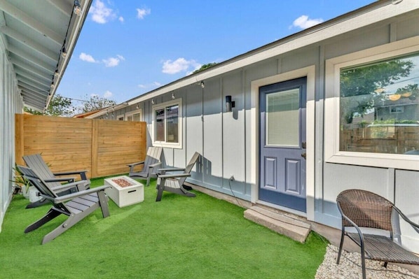 A residential property with a covered patio area, outdoor seating, and a wooden fence.