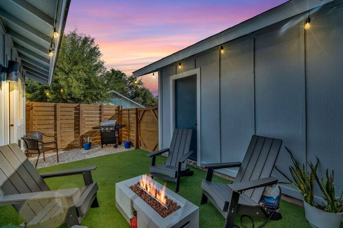 A backyard with a fire pit, outdoor seating, and a wooden fence.