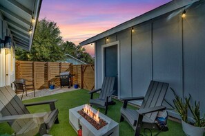 Un patio trasero con un hogar, mobiliario exterior y una valla de madera.