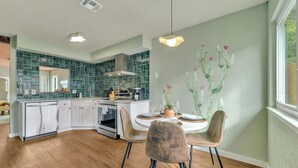 A modern kitchen with a central island, white cabinetry, and a green backsplash.