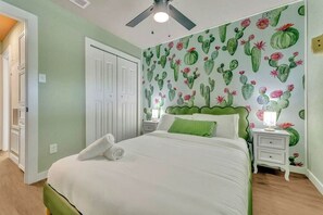 A bedroom with a bed, nightstands, a ceiling fan, and a door.