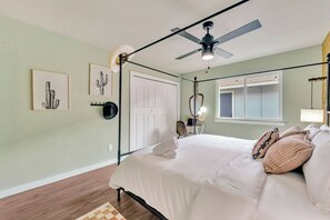 A bedroom with a four-poster bed, a ceiling fan, and artwork on the walls.