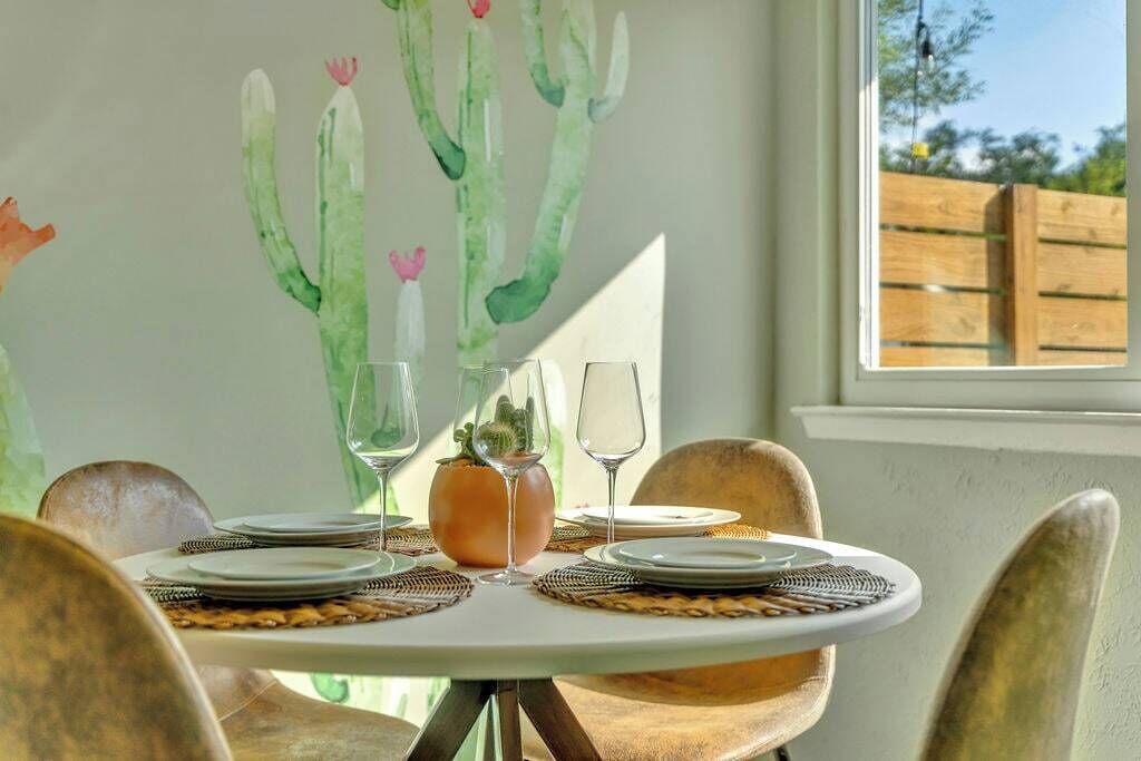A dining table set with plates, glasses, and a cactus centerpiece, with chairs around it.