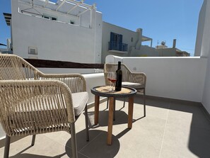 A balcony with wicker chairs and a small round table, a bottle of wine, and a glass. - THEOFANIS STUDIOS (Naxos)