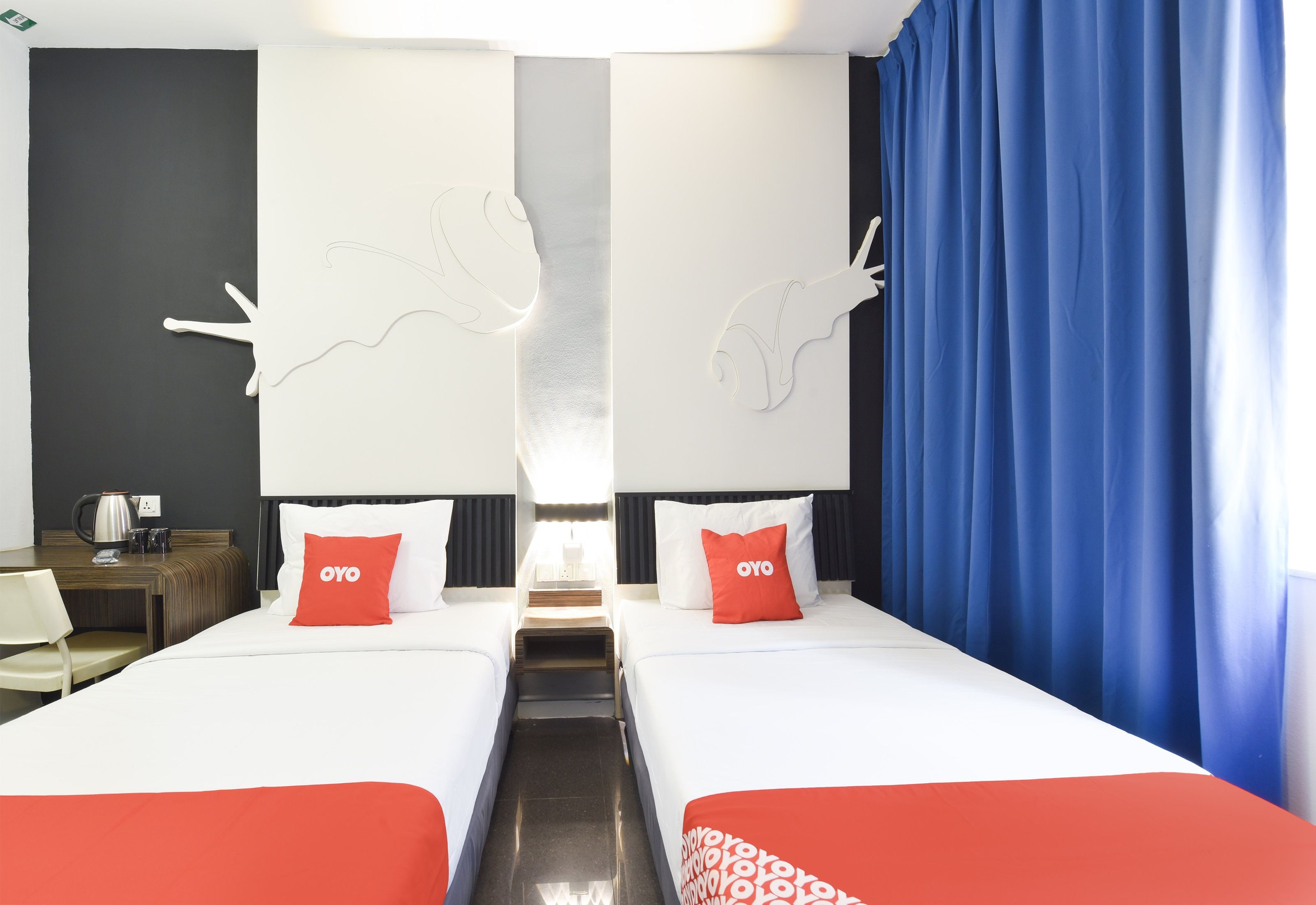 A hotel room with two beds, a coffee maker, and a nightstand.