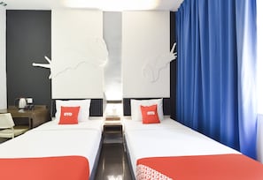 A hotel room with two beds, a coffee maker, and a nightstand.