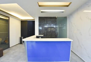 Een receptiebalie met een blauw blad, een marmeren wand en een modern plafondontwerp.