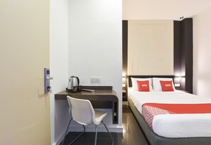 Ein Hotelzimmer mit Schreibtisch, Stuhl, Bett und Nachttisch.