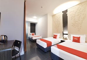 A hotel room with two beds, a desk, and a chair.