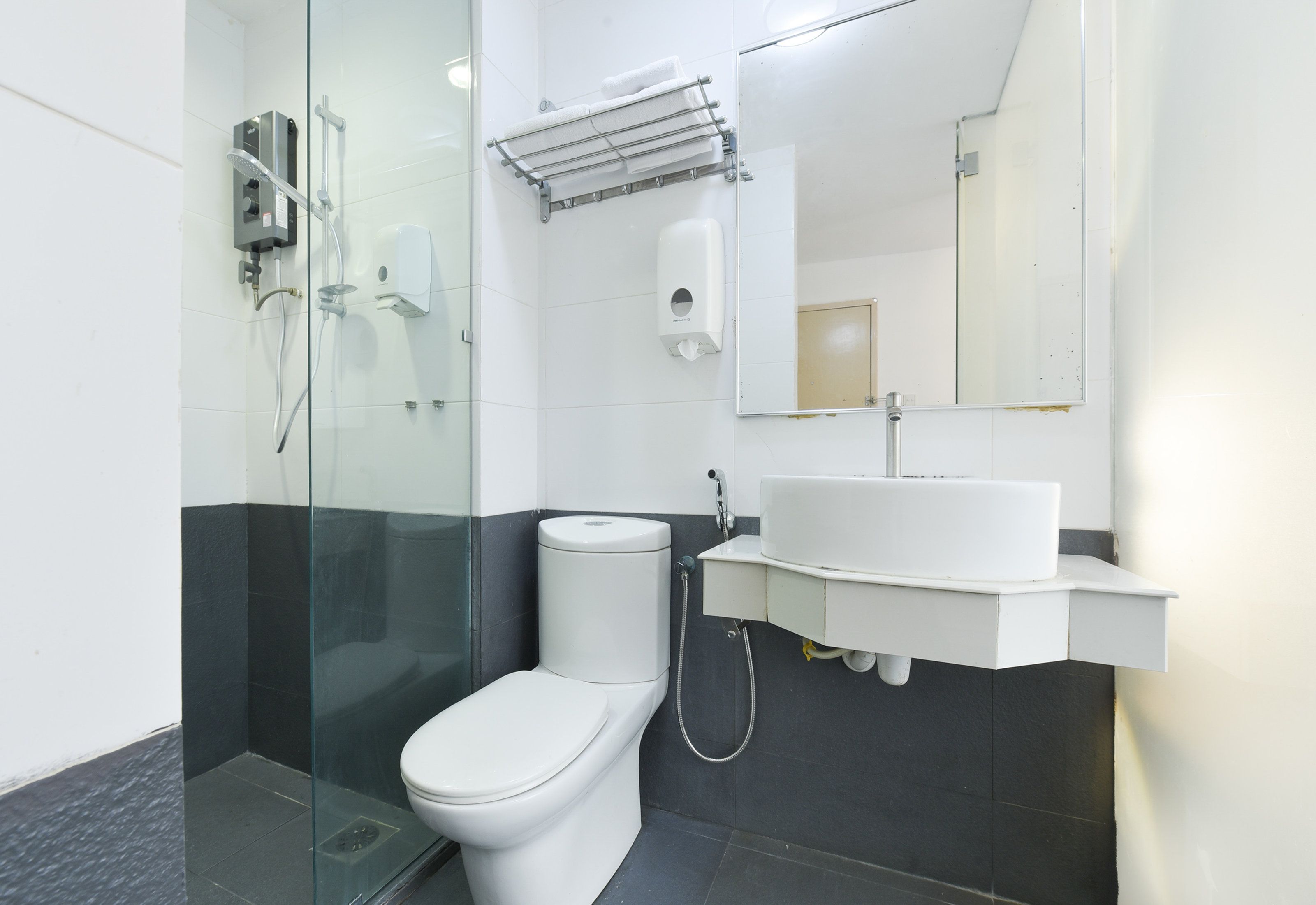 A modern bathroom with a glass shower enclosure, a white toilet, and a sink with a mirror above it.