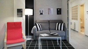 A modern living room with a grey sofa, a red chair, a floor lamp, and a small table with a remote control. - Laidatxu Beach Apartment in Mundaka (Mundaka)