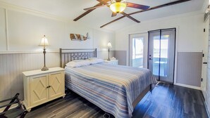 A bedroom with a bed, nightstands, a ceiling fan, and a window with blinds.