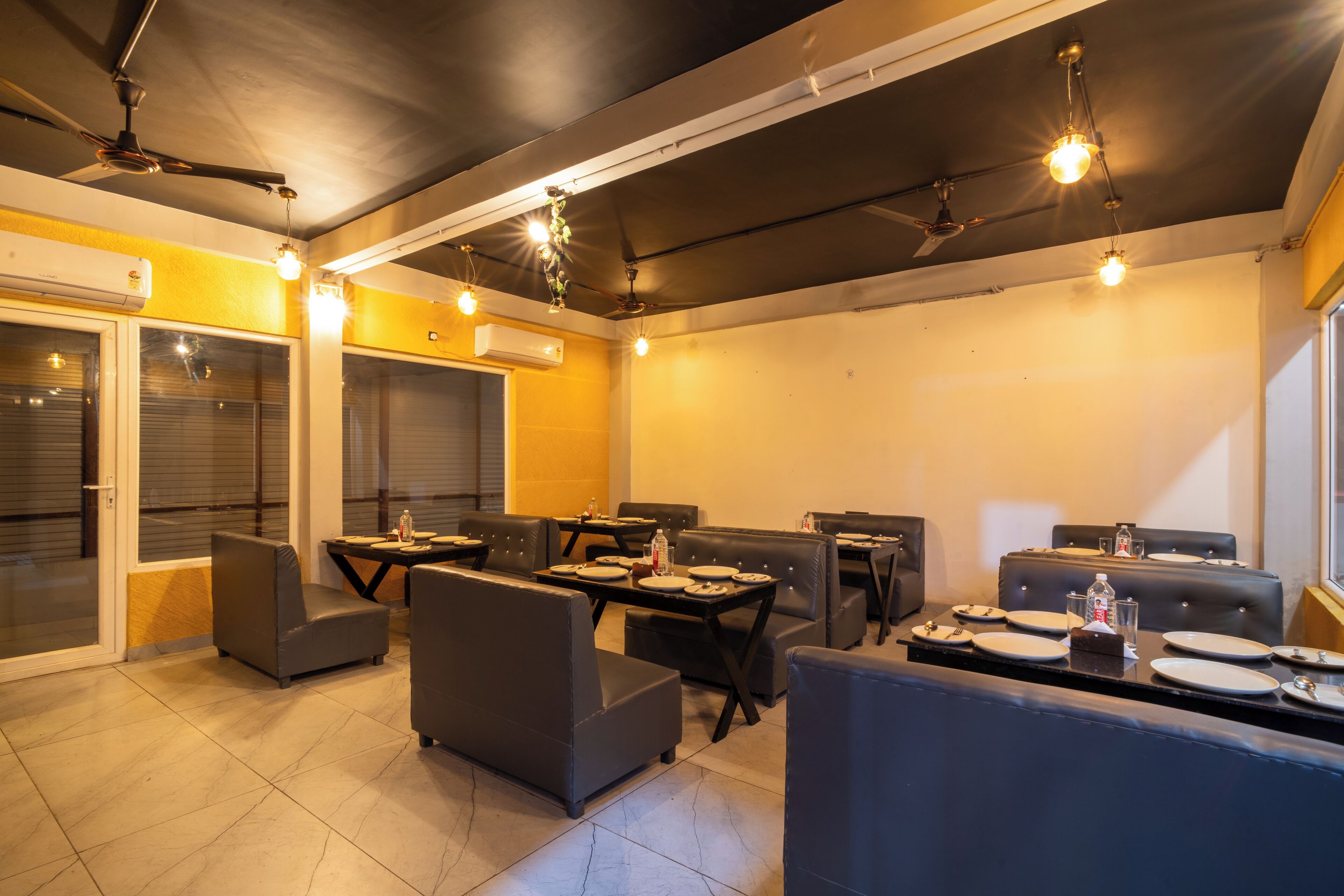 A restaurant with leather seating, tables set with plates and glasses, and pendant lighting.
