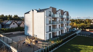 A multi-story residential building with balconies, a playground, and a parking area. - Apartamenty Sun & Snow Kuracyjna Jastrzębia Góra (Wladyslawowo)