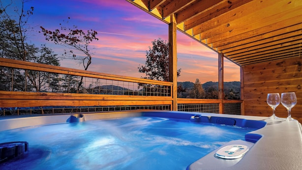 Een hottub met een houten terras en een tafel met twee glazen.