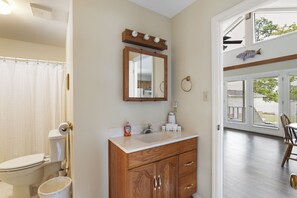 A bathroom with a toilet, sink, vanity, and a mirror. - Serenity on the Lake (Prosperity)