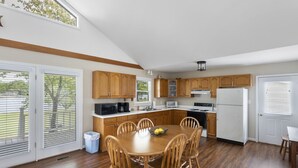 A spacious kitchen with wooden cabinets, a dining table with chairs, and a large window providing natural light. - Serenity on the Lake (Prosperity)
