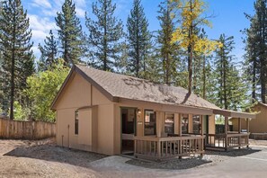 A single-story building with a sloped roof, a porch with railings, and a fenced yard. - Bearfoot Bungalow - Year Round Private Beach Access (Tahoe Vista)