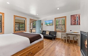 A bedroom with a bed, a desk, a fireplace, and large windows. - Bearfoot Bungalow - Year Round Private Beach Access (Tahoe Vista)