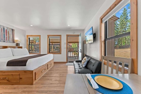 A bedroom with a bed, a sofa, a dining table with a plate, and a TV.