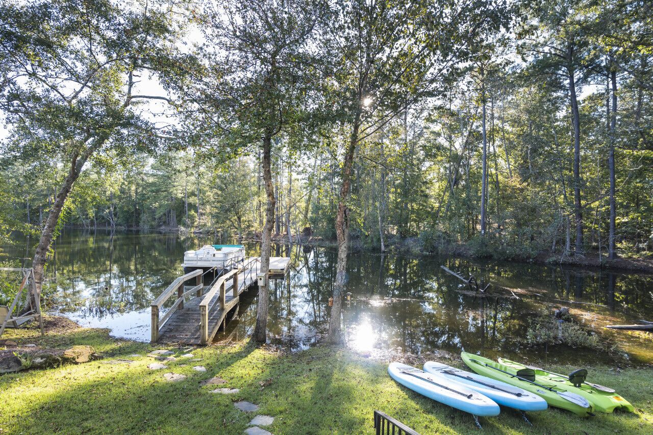 A serene lakeside setting with a wooden dock and kayaks.