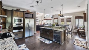 A spacious kitchen with dark wood cabinets, stainless steel appliances, and a large island.