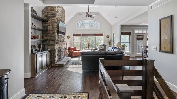 A spacious living area with a stone fireplace, a large window, and a cozy seating arrangement.