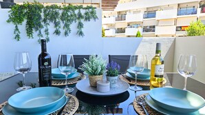 A dining table set with blue plates, wine glasses, and bottles, surrounded by woven placemats and a small potted plant. - Two bedroom apartment in Riviera del sol (Mijas Costa)