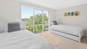 Une chambre avec deux lits, de grandes fenêtres et une vue sur la verdure.
