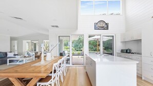 Une cuisine moderne avec une table à manger en bois, des meubles blancs et une vue sur le jardin.