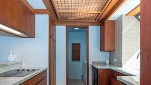 Een keuken met houten kastjes, een betegelde spatwand en een plafond met ruitmotief.