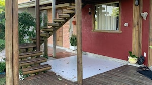 A wooden deck with a staircase leading to a covered area with a glass window. - Camaleao Ecopousada Ltda (Linhares)