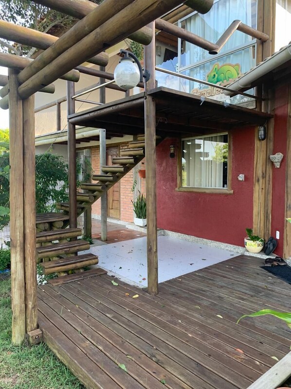 A wooden deck with a staircase leading to a covered area with a glass window.